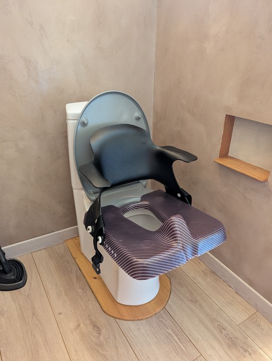 Réducteur avec dossier s’emboîtant sur la lunette des WC.
Maintien postural modéré.